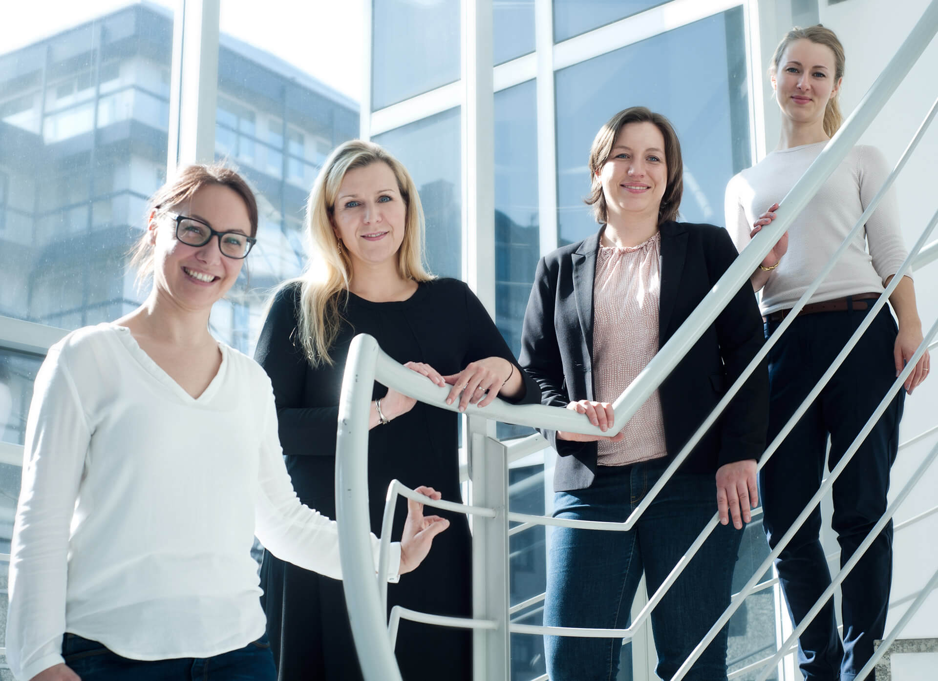 Vier Damen im Geschäfts Kleidung stehen auf einer Treppe vor einem Business - Bauwerk