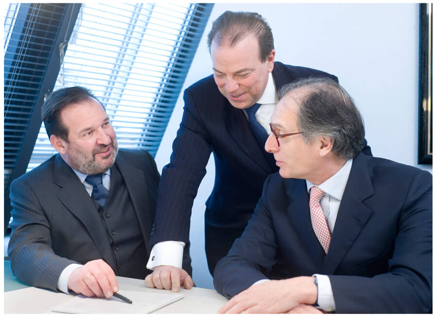 Firmenshooting, drei kollegen haben eine Besprechung im Büro, zwei davon sitzen, und einer steht in der Mitte, alle mit Krawatten