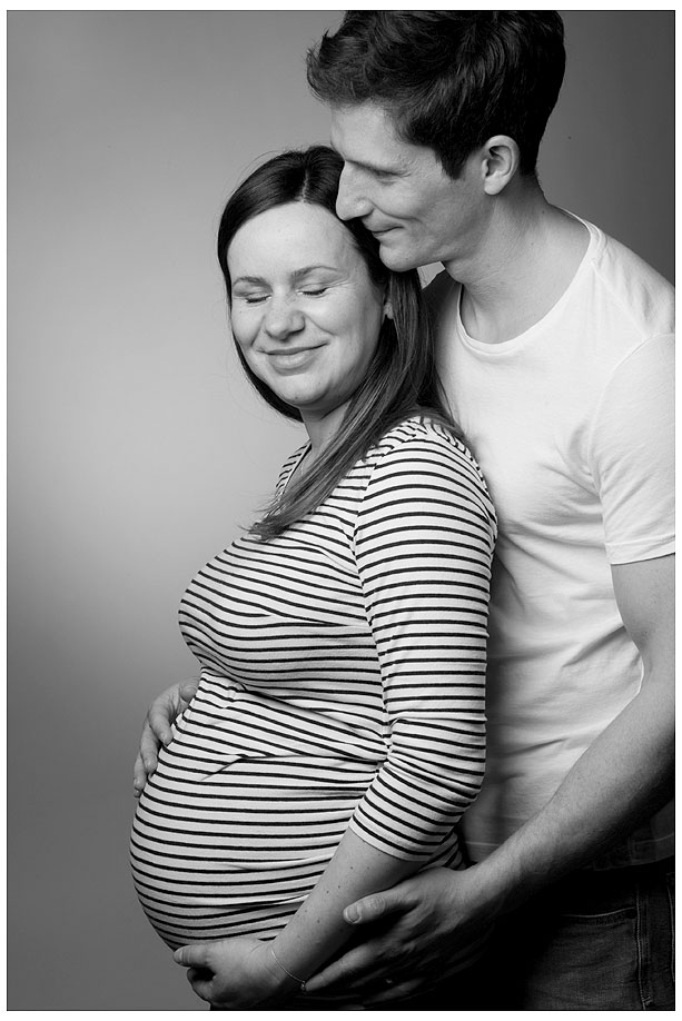 Eine schwangere Frau und ein Mann stehen für ein schwarz-weißes Foto in Pose