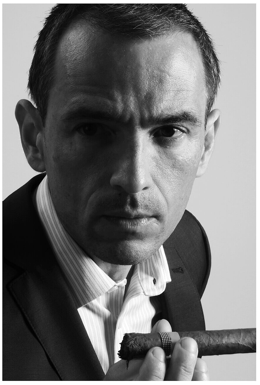 Ein Mann in Anzug hält eine Zigarre und schaut ernst für Fotografie Social Media