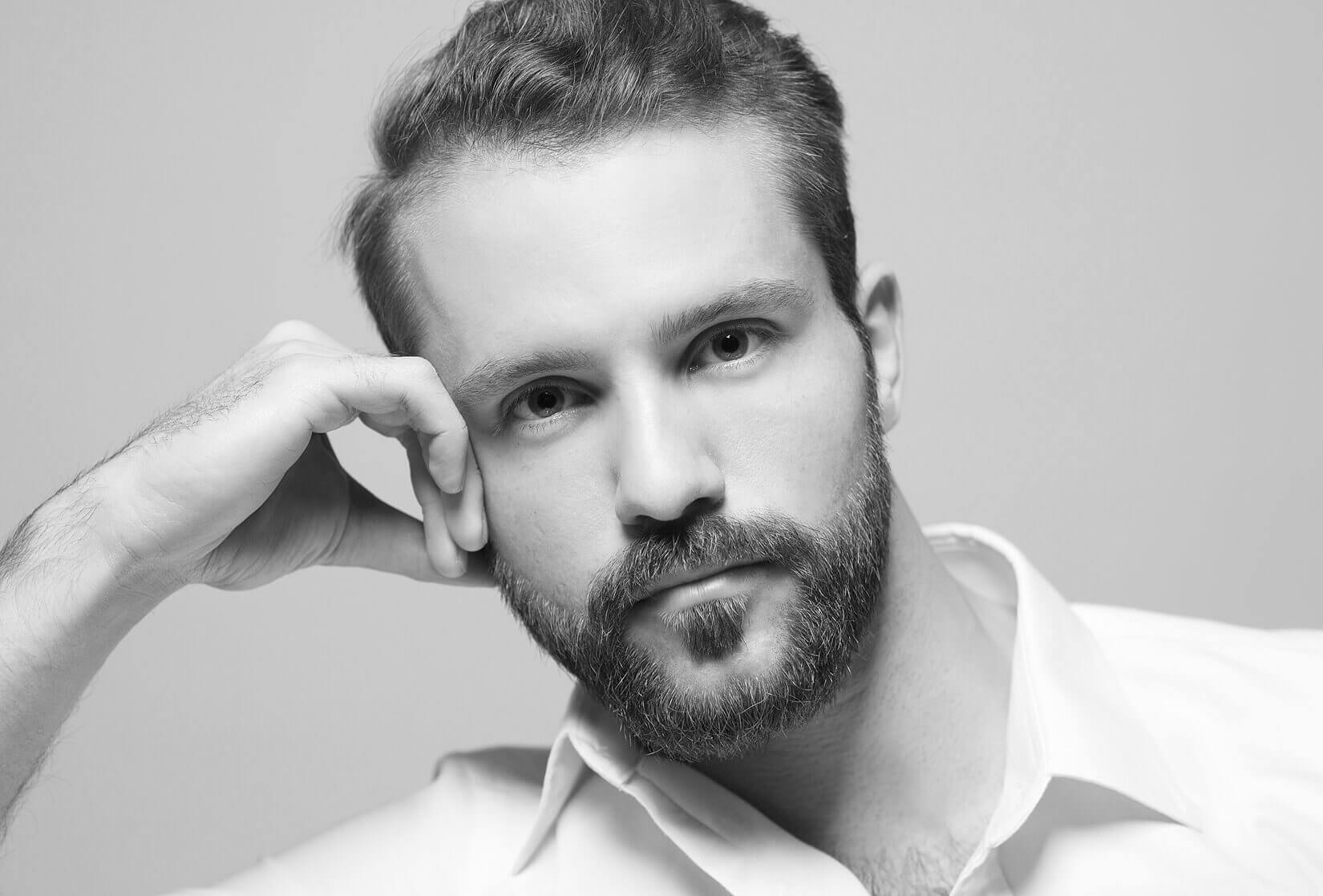 Ein bärtiger Mann mit weißem Hemd posiert für Fotografie Social Media