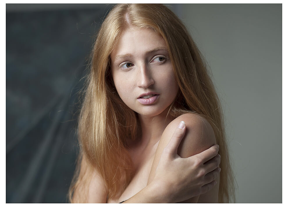 Eine attraktive junge Frau mit langen roten Haaren zeigt sich für Fotografie Social Media, schulterfrei