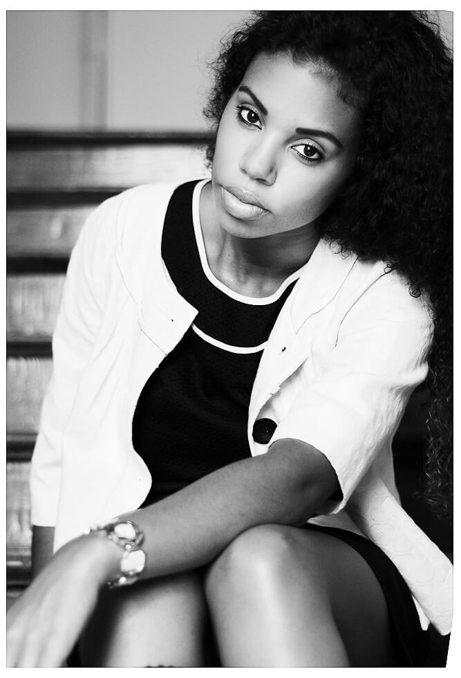 Schwarz-weiß Foto einer Frau mit afrikanischen Würzeln, die auf Treppen sitzt. Fotografie Social Media.