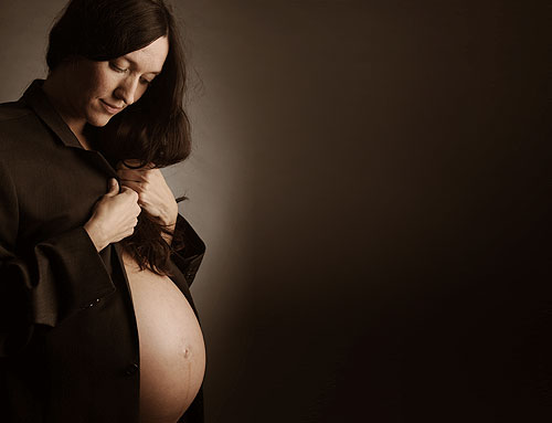 Babybauch Fotoshooting Eine schwangere Frau, gekleidet in einem schwarzen Anzug und schwarzer Bluse