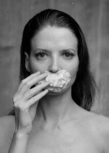 Schwarz-Weiß Portrait aus einem künstlerischen Model Shooting im Fotostudio Belichtungswert München mit Muschel, direktem Blick und analog wirkender Bildästhetik.
