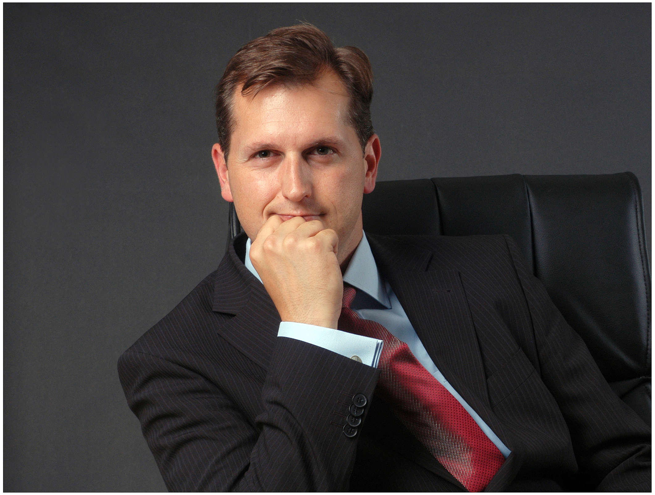 business-portrait-mann-im-anzug-sitzend-hand-am-gesicht-nachdenklicher-blick