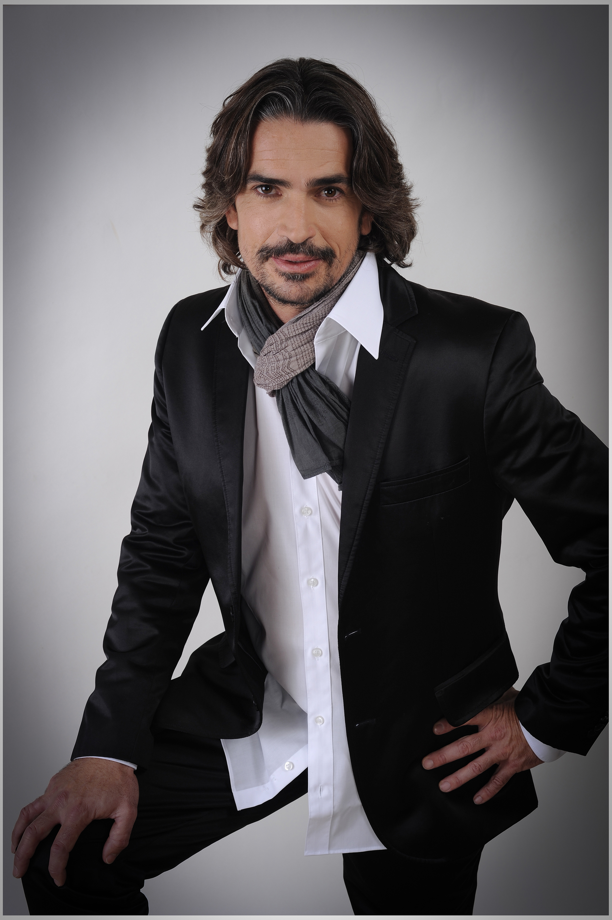 Männliches-Model-in-schwarzem-Shirt-mit-verschränkten-Armen-vor-dunklem-Hintergrund