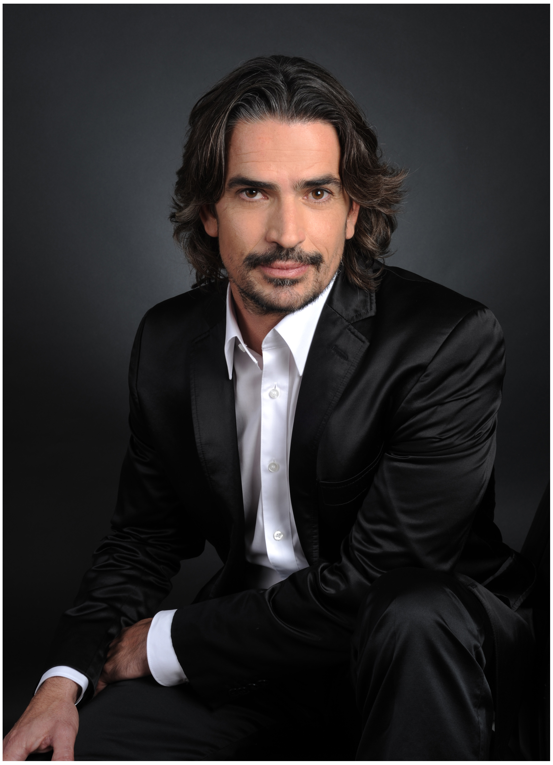 Model Fotoshooting Mann im schwarzen Anzug im Studio mit direktem Blick und klassischer Pose Dunkel