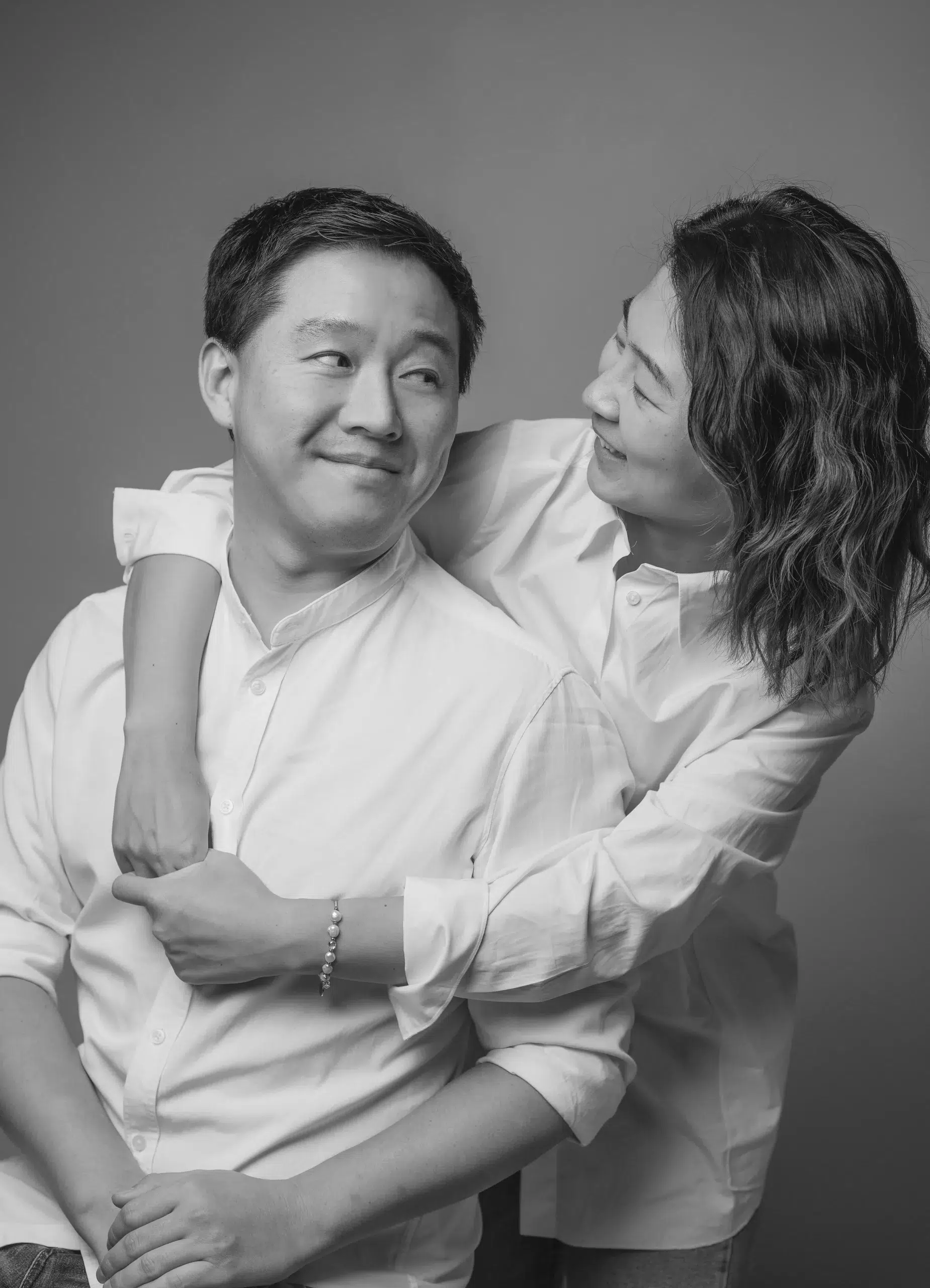 Ein schwarz-weißes Foto zeigt ein Paar, das sich umarmt. Die beiden Personen stehen eng beieinander und wirken glücklich und vertraut miteinander. Die Umarmung strahlt Wärme und Zuneigung aus.