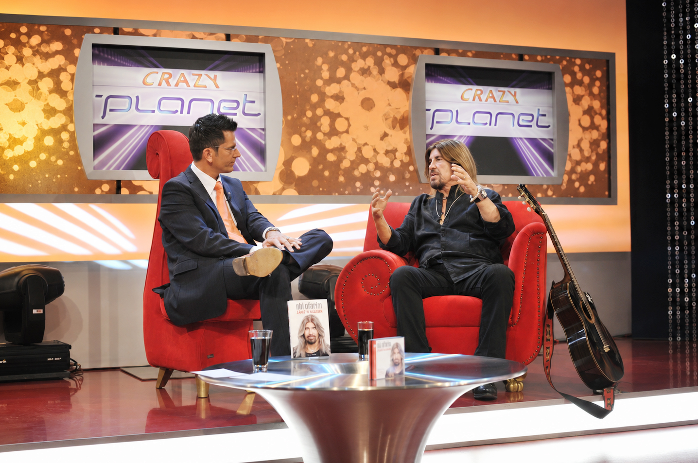 Abi Ofarim bei seinem letzten Fernsehinterview vor seinem Tod in der Neun-Live-Sendung Crazy Planet mit Moderator Thomas Schürmann, sitzend im roten Sessel im TV-Studio neben seiner Gitarre.