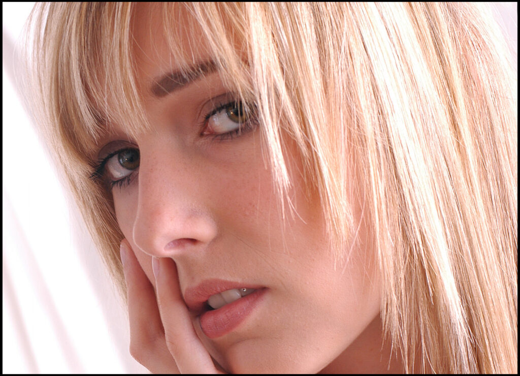 Beauty-Fotoshooting Outdoor vom Fotostudio Belichtungswert München, Close-up einer jungen blonden Frau mit weichem Licht, glattem Haar und leicht laszivem Blick