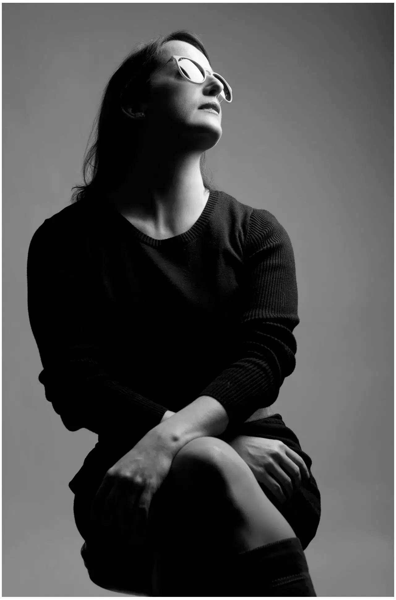 Eine Frau sitzt auf einem Hocker und trägt eine Brille