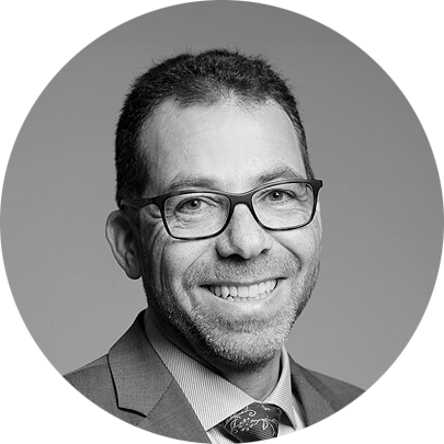 Schwarz-Weiß-Bewerbungsfoto eines lächelnden Geschäftsmanns mit Brille und Krawatte im runden LinkedIn-Profilbild-Schnitt