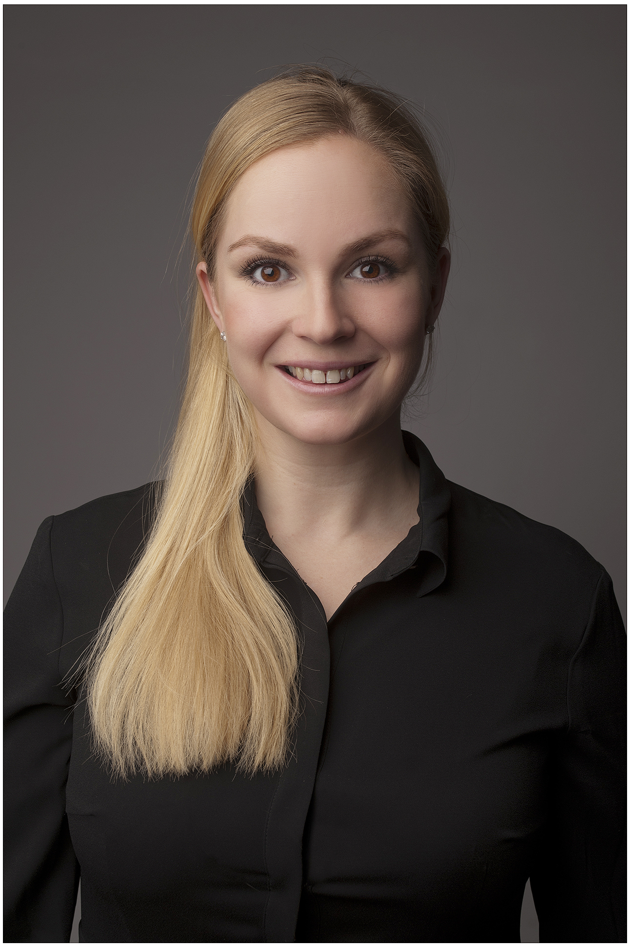 management-businessportrait-im-studio-blonde-frau-in-schwarzer-bluse-laechelnd-klare-augen-dunkler-hintergrund-hochwertiger-look