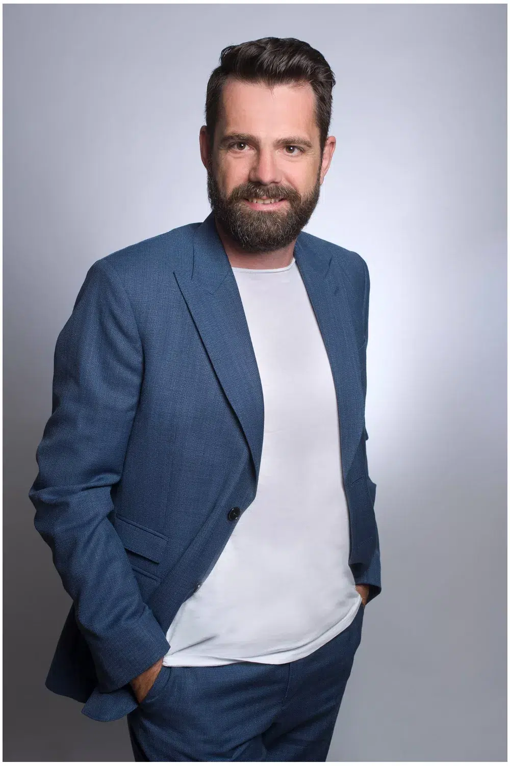 Mann mit Bart laechelt in die kamera, stehend für Businessportrait München