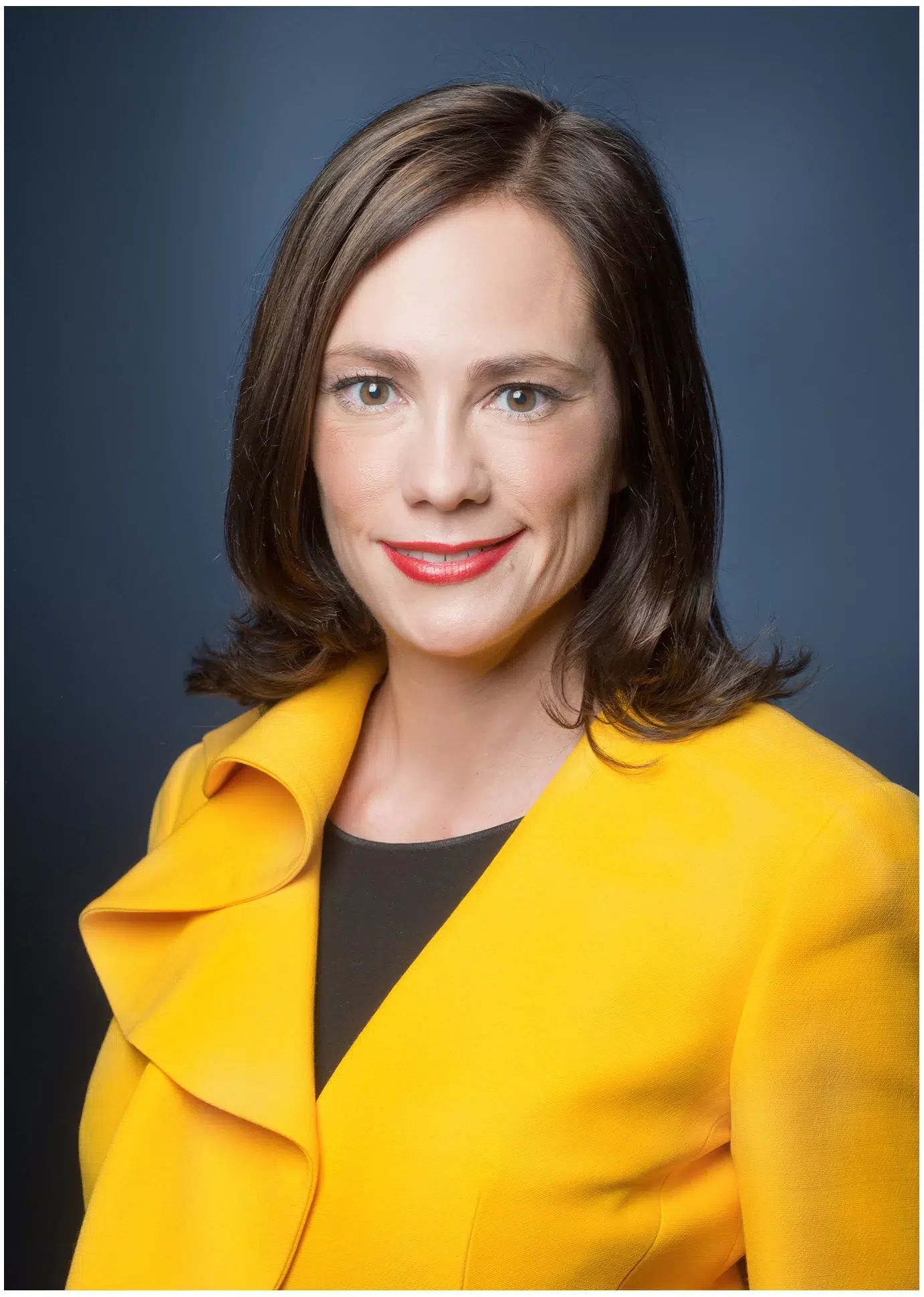 Businessportrait einer Frau in gelber Jacke und schwarzem Top