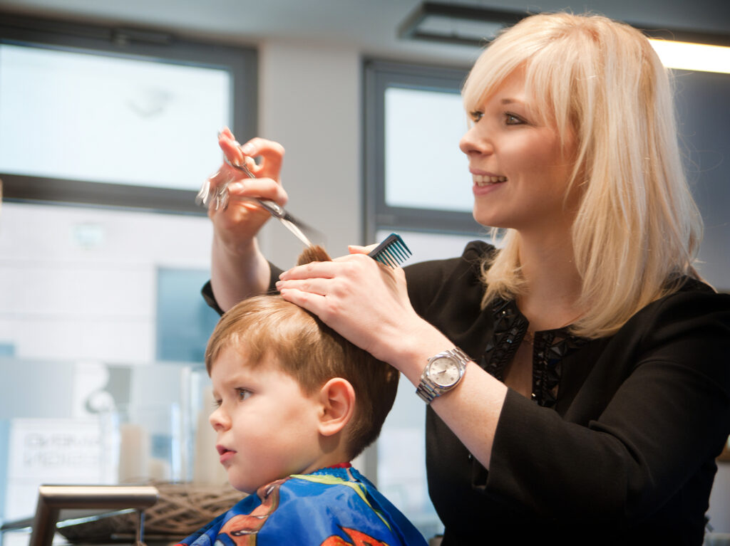 Reportagefoto im Friseursalon: Kinderhaarschnitt, konzentrierte Arbeit, authentischer Moment – Unternehmensfotografie München Schwabing