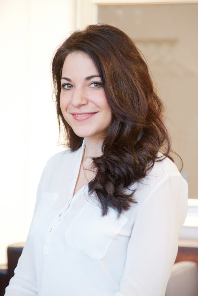 Businessportrait einer Friseur-Mitarbeiterin im Salon: brünett, weiße Bluse, sympathisches Lächeln – Brandingfotos München Schwabing