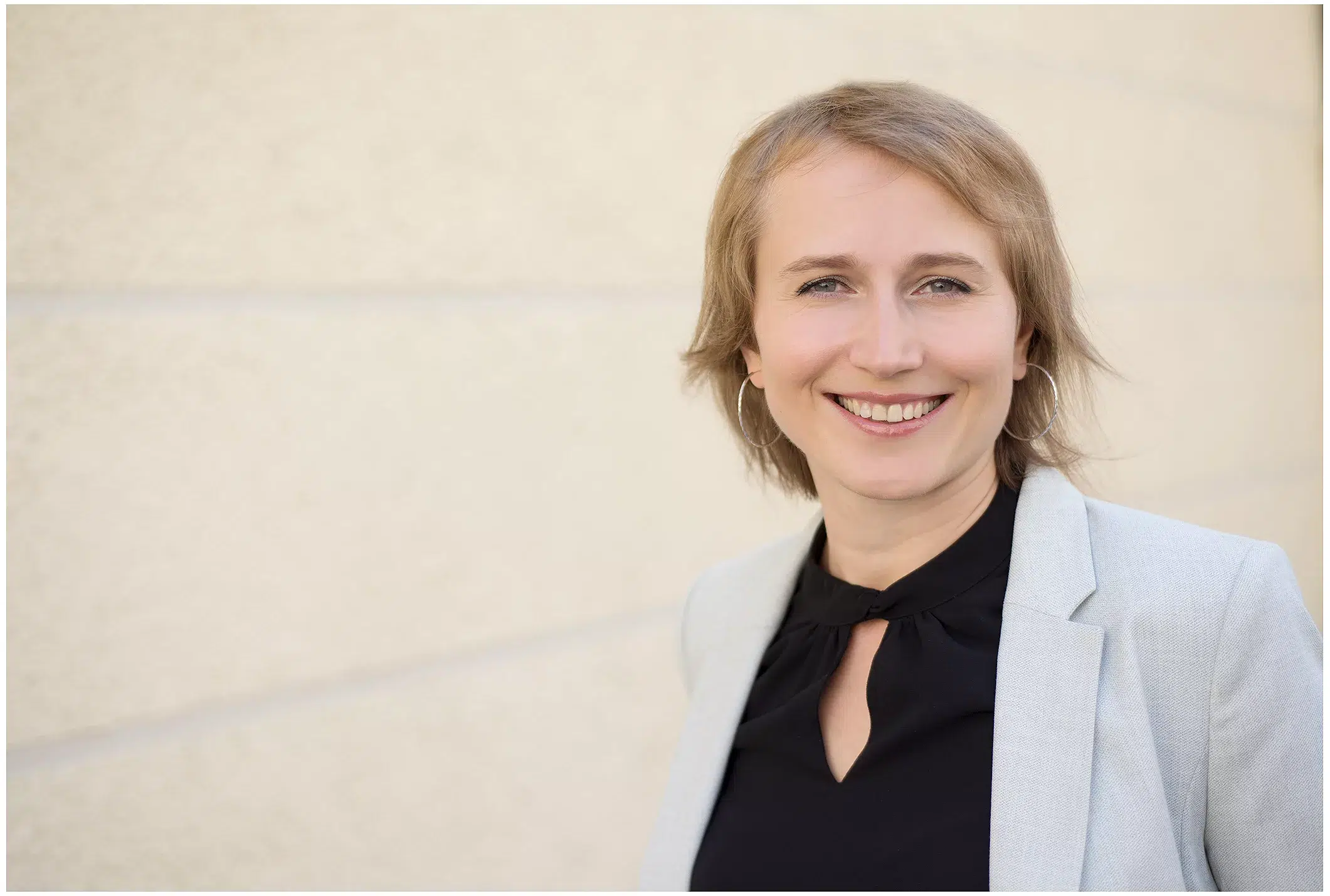 Junge Frau im hellen Blazer und schwarzem Oberteil draussen beim Fotoshooting