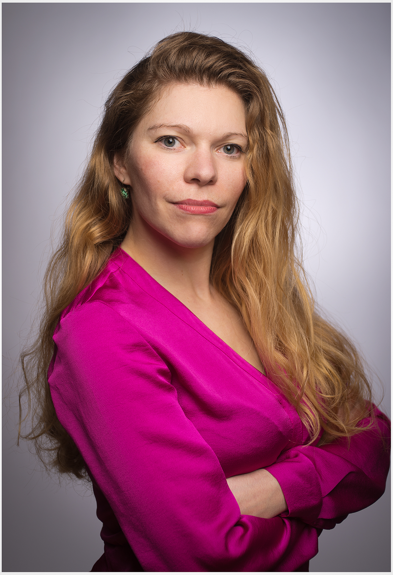 Serioeses Businessportrait einer blonden Frau mit verschraenkten Armen und direktem Blick im Fotostudio Businessfoto fuer Firmen in Muenchen