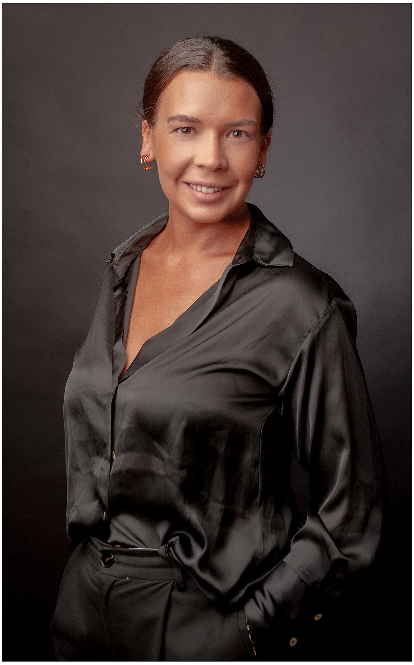 Eine Frau mittlerer Alter in einem schwarzen Hemd posiert für ein Businessportrait