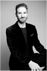 Businessportrait München Mann sitzend auf einem Stuhl im Studio, lächelnd, schwarz-weiss,