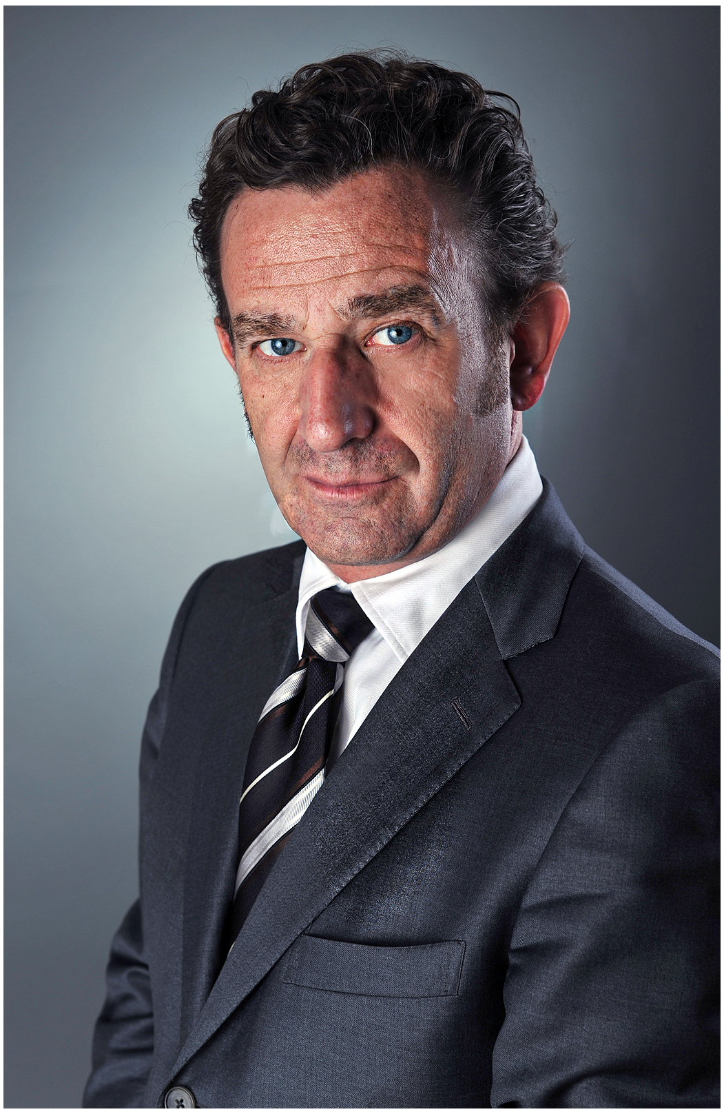 executive-portrait-finance-banking-manager-im-anzug-mit-krawatte-serioeser-blick-studio-dunkler-hintergrund