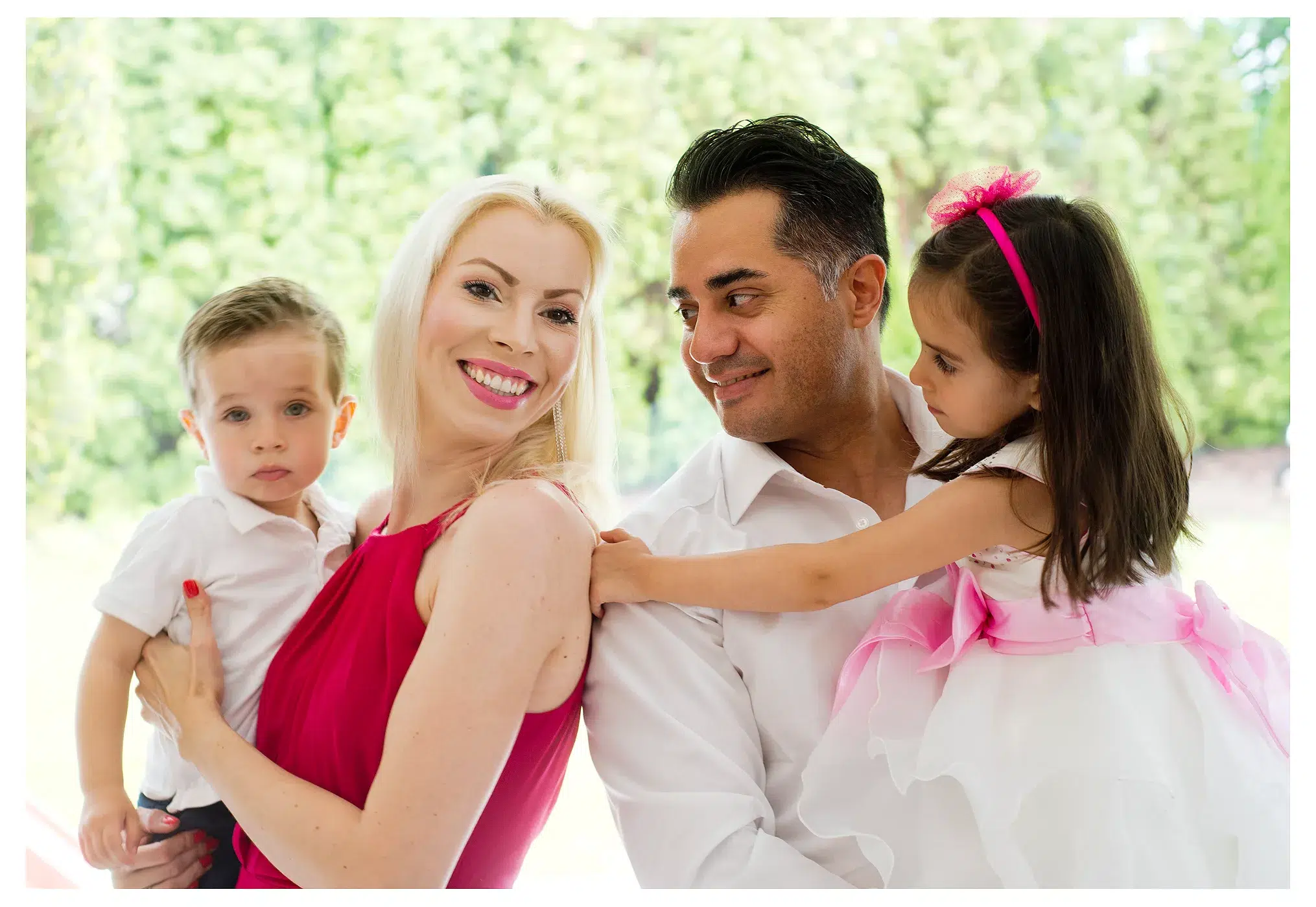 Familienfoto, alle lächeln, mama und Sohn schauen in die Kamera, gruener hintergrund