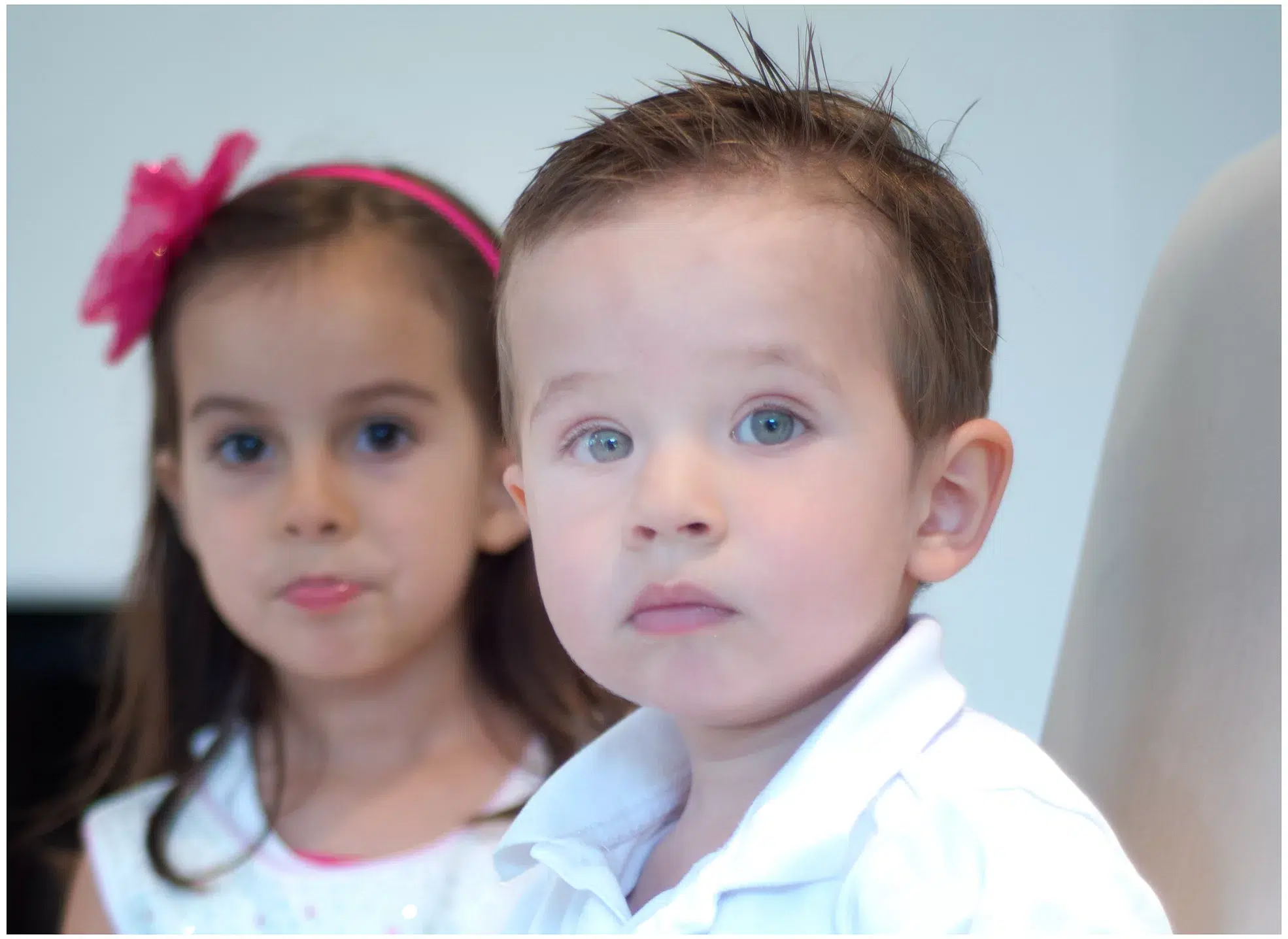 Familienfotoshooting, Junge schaut in die Kamera sehr ernst, Schwester im Hintergrund