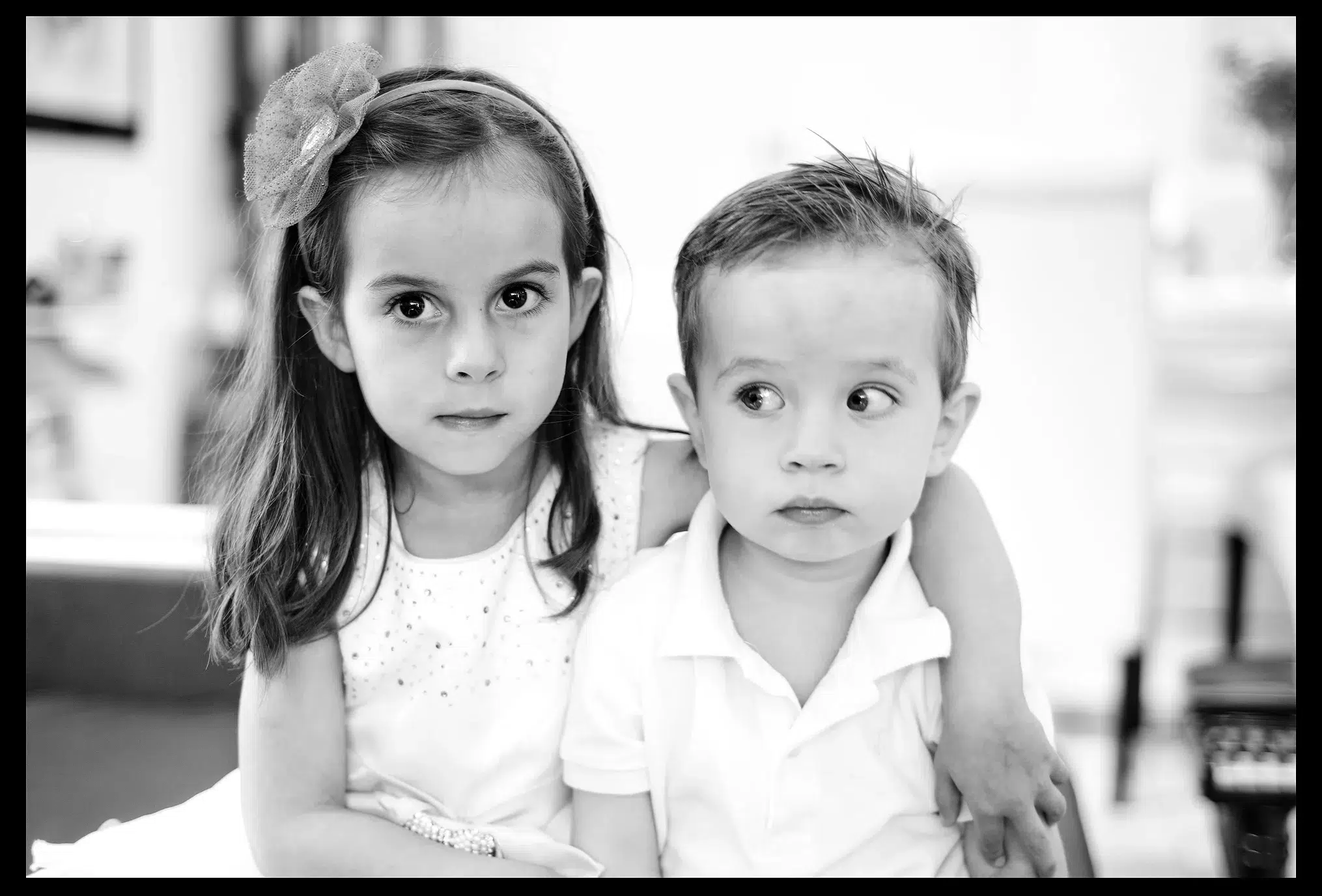 Zwei Kinder vor der Kamera, das Mädchen umarmt ihren Bruder, schwarz-weiss