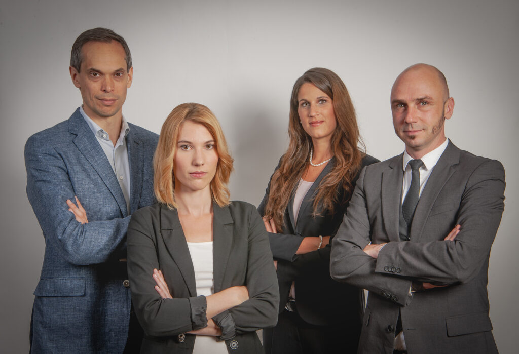 Professionelles Teamfoto aus einem Firmenshooting im Studio mit vier Personen im Business-Outfit vor grauem Hintergrund, aufgenommen bei Fotostudio Belichtungswert in München.