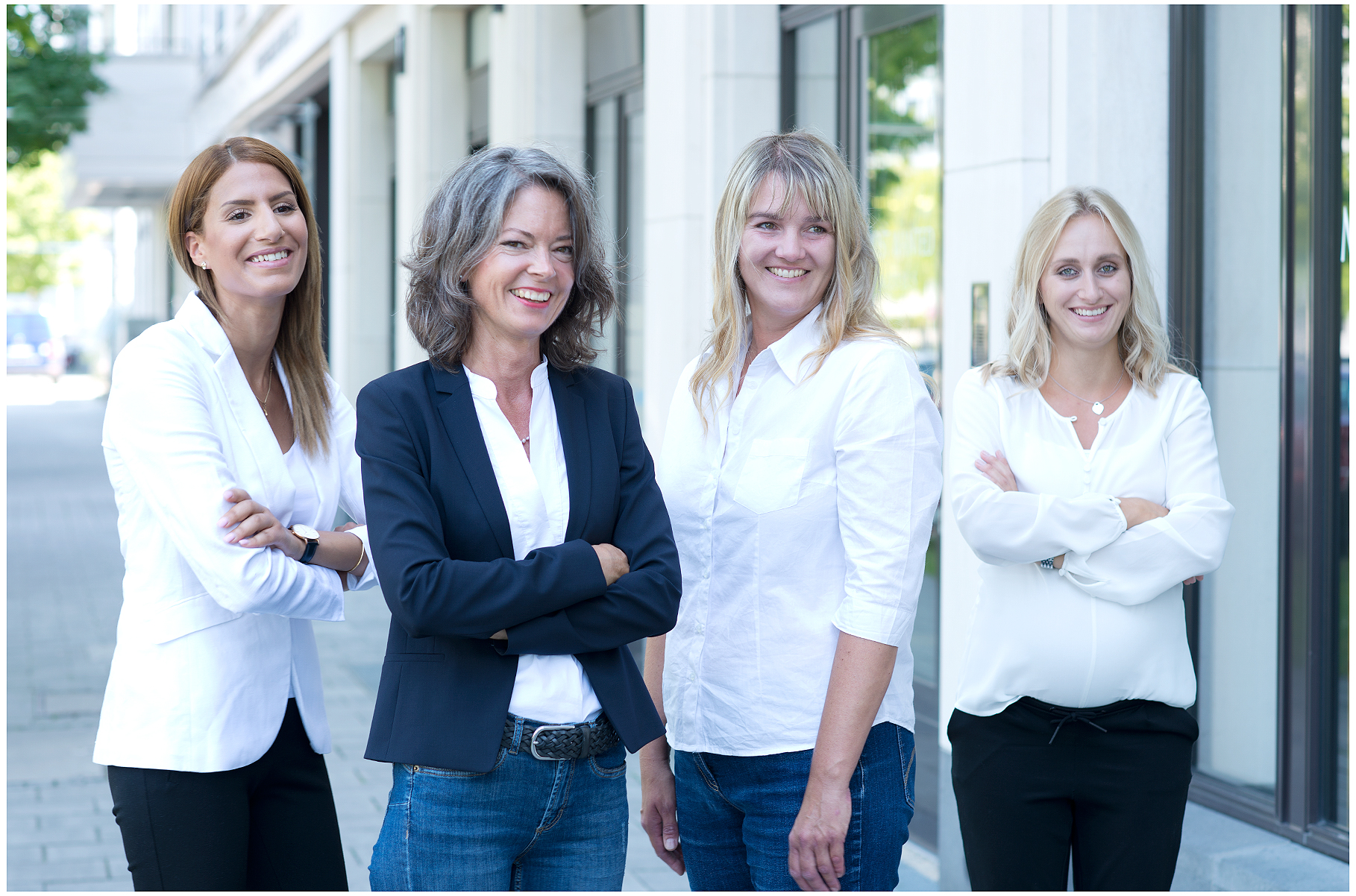 Firmenshooting vom Fotostudio Belichtungswert München, vier Frauen als professionelles Business-Team outdoor vor einem Bürogebäude, freundlich lächelnd