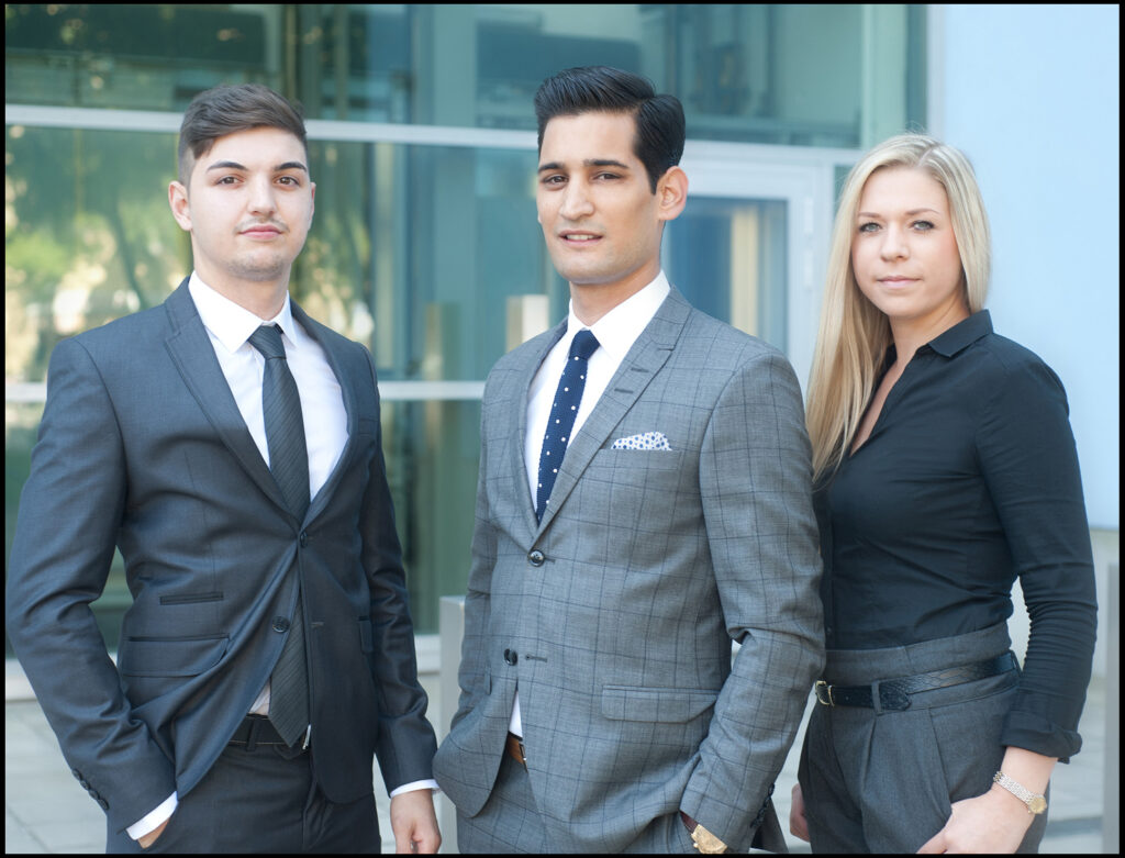 Teamportrait einer Immobilienfirma vom Fotostudio Belichtungswert München, drei junge Mitarbeiter stehen outdoor in Businesskleidung vor einer modernen Glasfassade