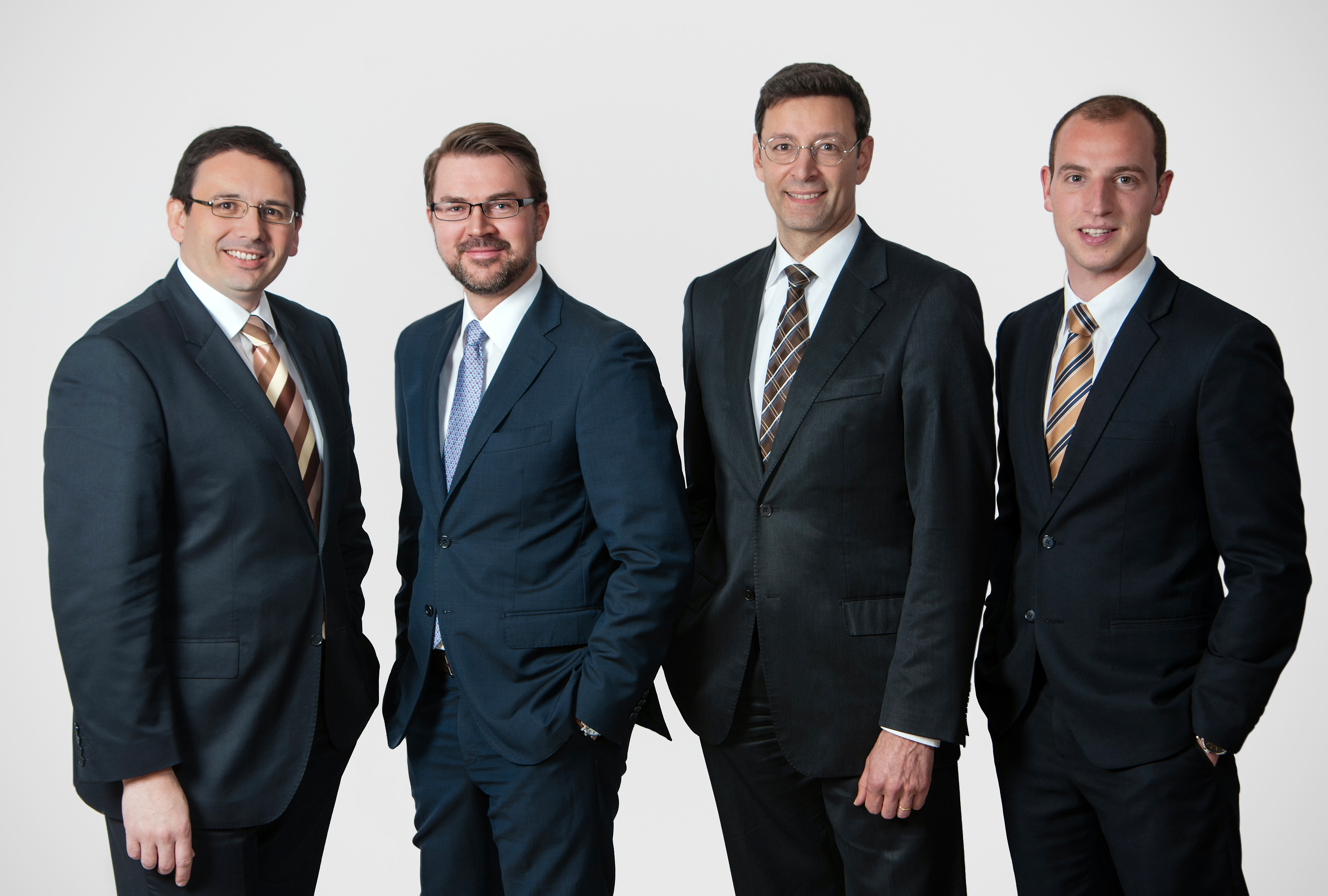 firmenshooting-teamfoto-vier-kollegen-im-business-anzug-sympathisch-souveraen-heller-studiohintergrund