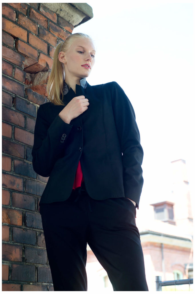 Fotograf in München fotografiert ein blondes Model an der alten Wand, von unten fotografiert, Haende verschraenkt,