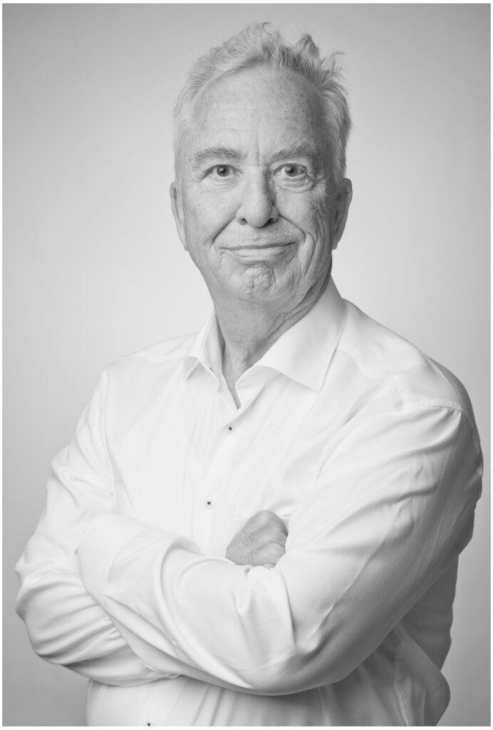 Komparsen-Sedcard vom Fotostudio Belichtungswert München, Best-Age-Mann im Schwarzweiß-Portrait mit weißem Hemd, verschränkten Armen und freundlichem souveränem Blick