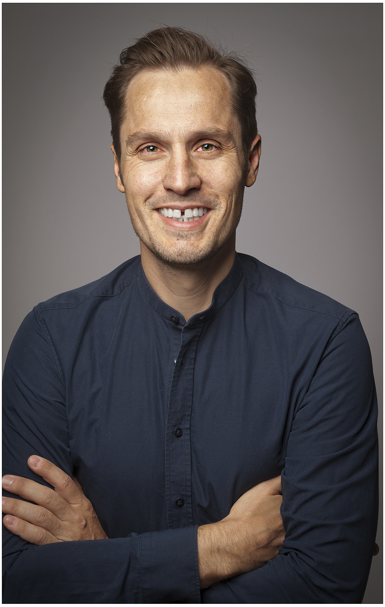 legere-businessportrait-mann-arme-verschränkt-dunkles-hemd-sympathisch-studio-dunkler-hintergrund