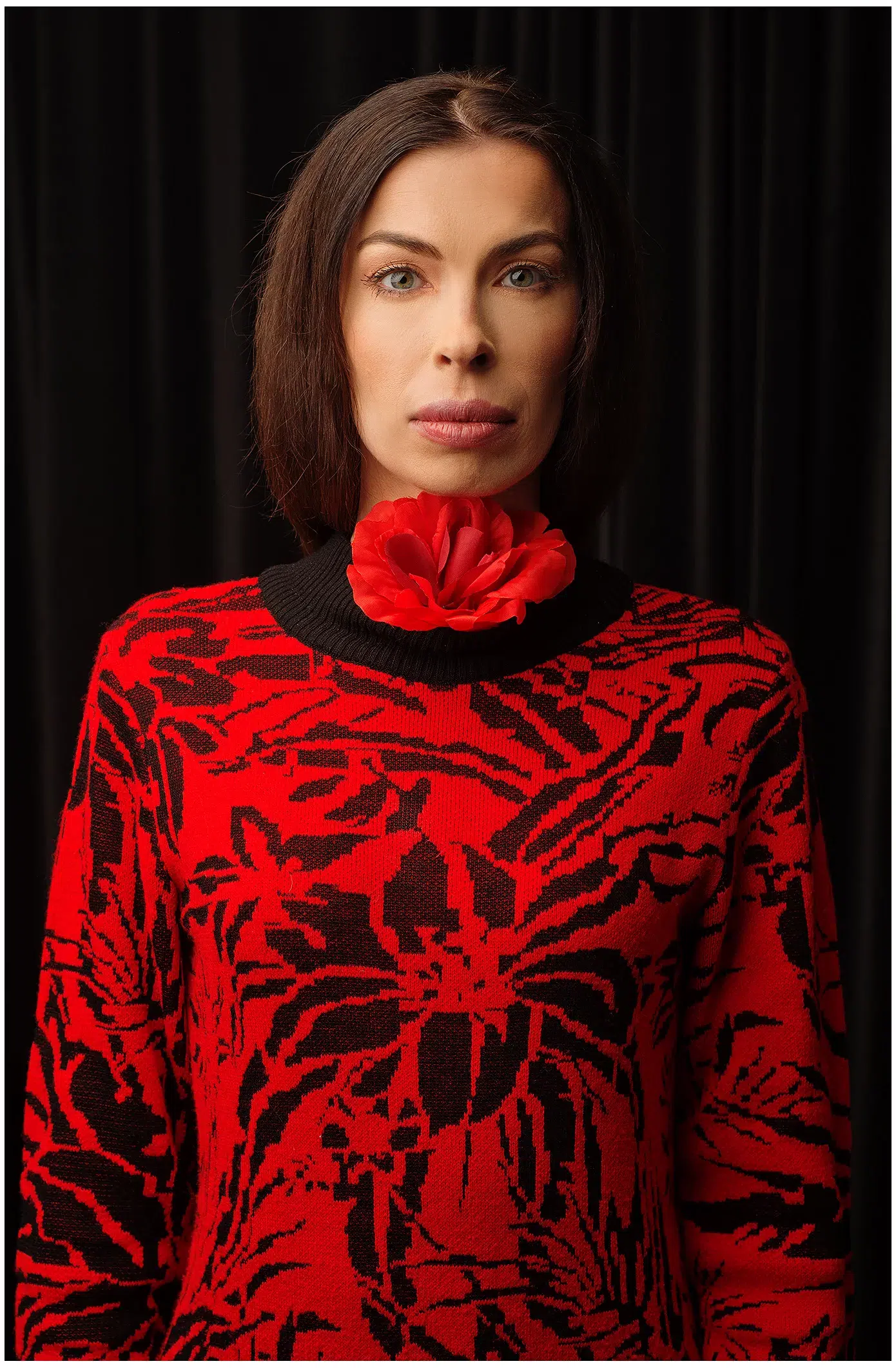 Model für Sedcard im roten Kleid steht frontal vor der Kamera, mit der Kunstblume im Kragen