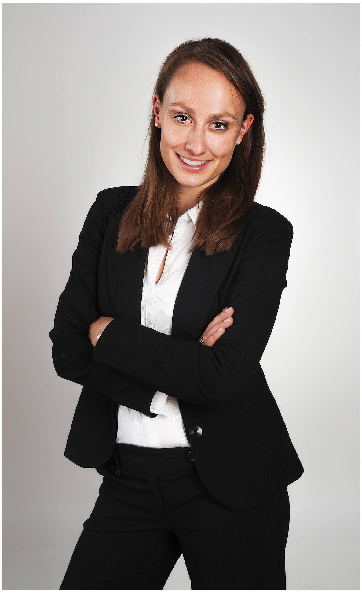modernes-businessfoto-im-studio-frau-im-schwarzen-blazer-und-weisser-bluse-mit-verschränkten-armen-souveräner-blick-heller-hintergrund