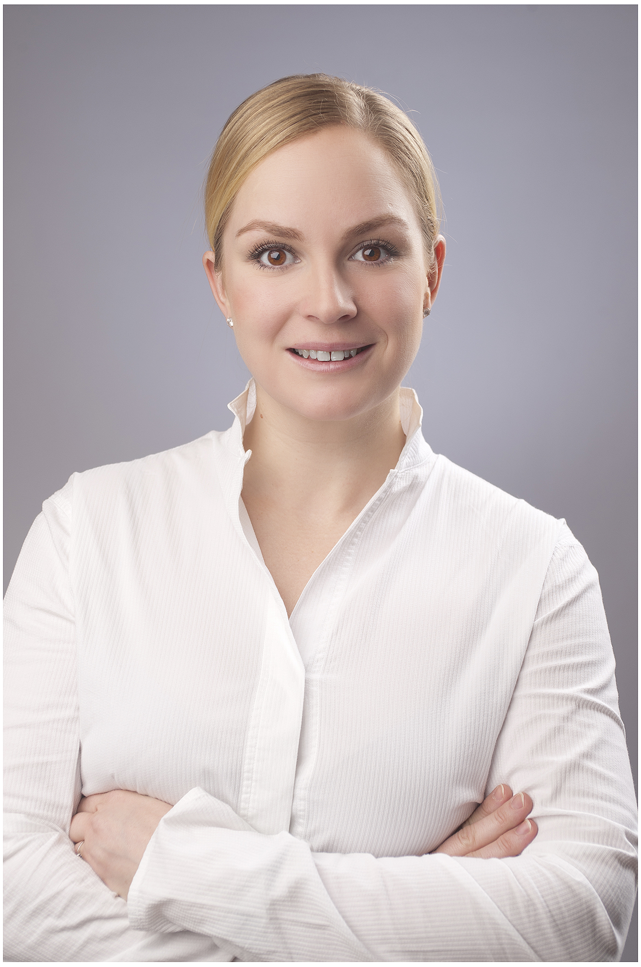 modernes-businessportrait-im-studio-blonde-frau-in-weisser-bluse-arme-verschränkt-ruhiger-blick-heller-neutraler-hintergrund