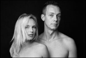 Paarshooting im Fotostudio Belichtungswert München – Schwarz-Weiß-Portrait eines oben ohne posierenden Paares vor dunklem Hintergrund