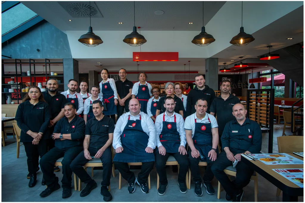 Ein Gruppenfoto der Mitarbeiter in einem Schnell Food Restaurant, alle uniformiert, sitzend