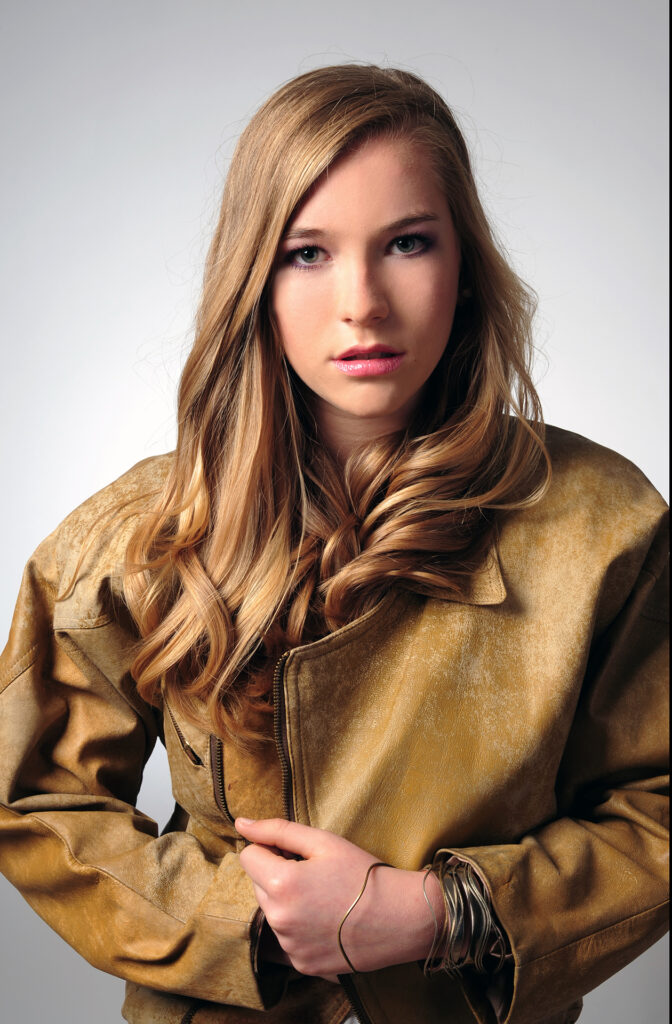 Portrait für Dating-Profil und Online-Profile vom Fotostudio Belichtungswert München, junges Mädchen als Fashion-Portrait mit brauner Jacke, langen blonden Haaren und direktem Blick