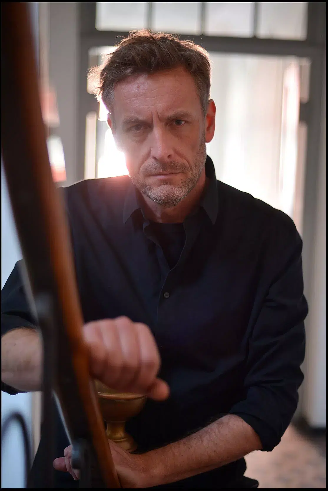Portrait eines Musikers draußen im Treppenhaus, schwarzes Hemd, farbig
