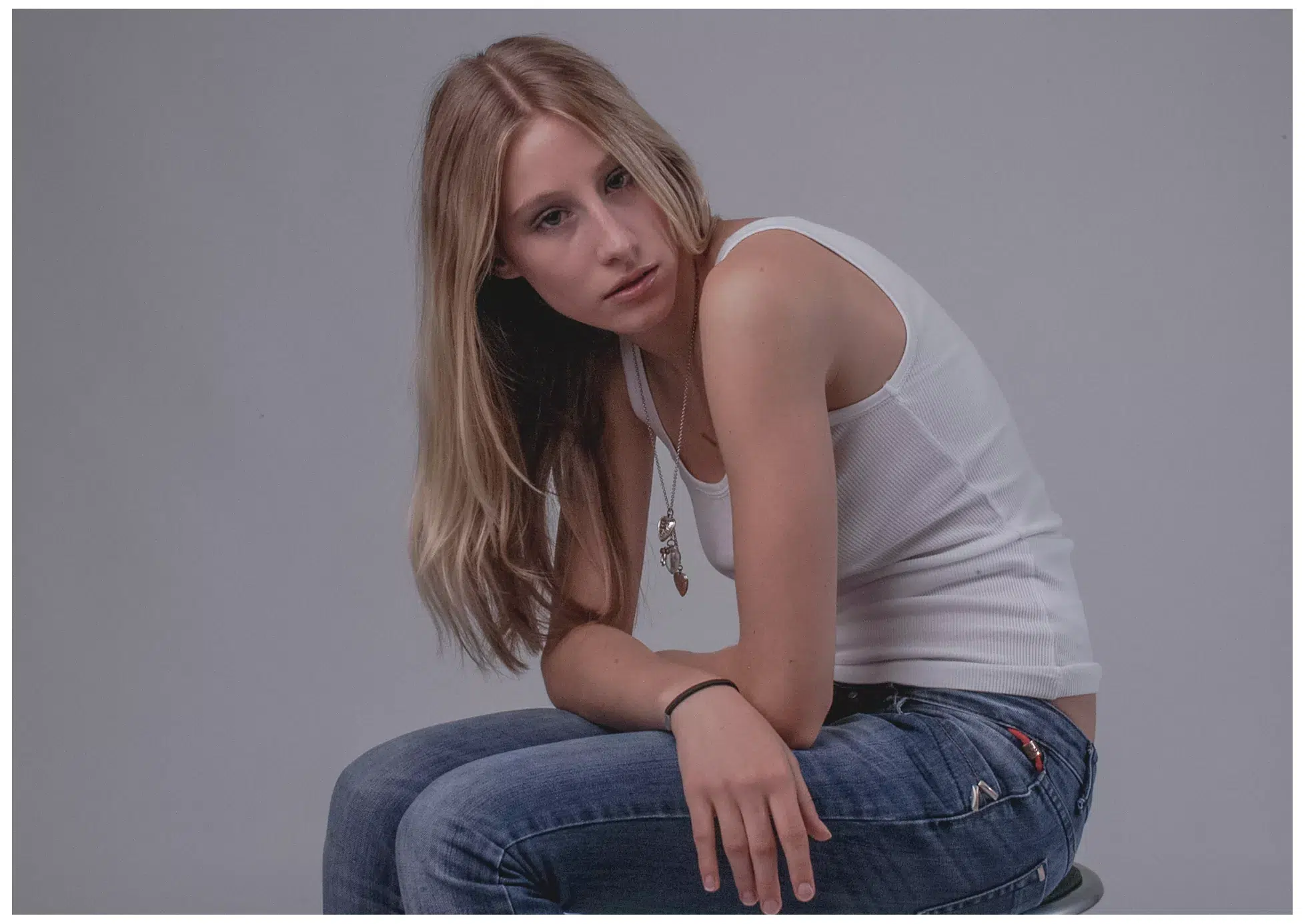 Ann-Sophie, Model im weißen Shirt und Jeans, sitzt auf dem Hocker und schaut in die Kamera
