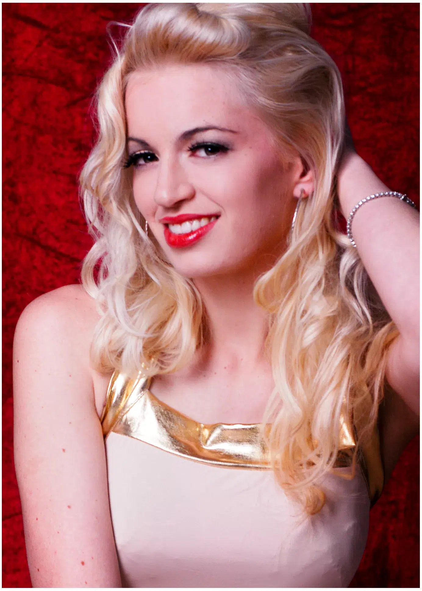 Blondes Model Antonia, sexy mit rotem Hintergrund, streicht über die Haare mit der Hand
